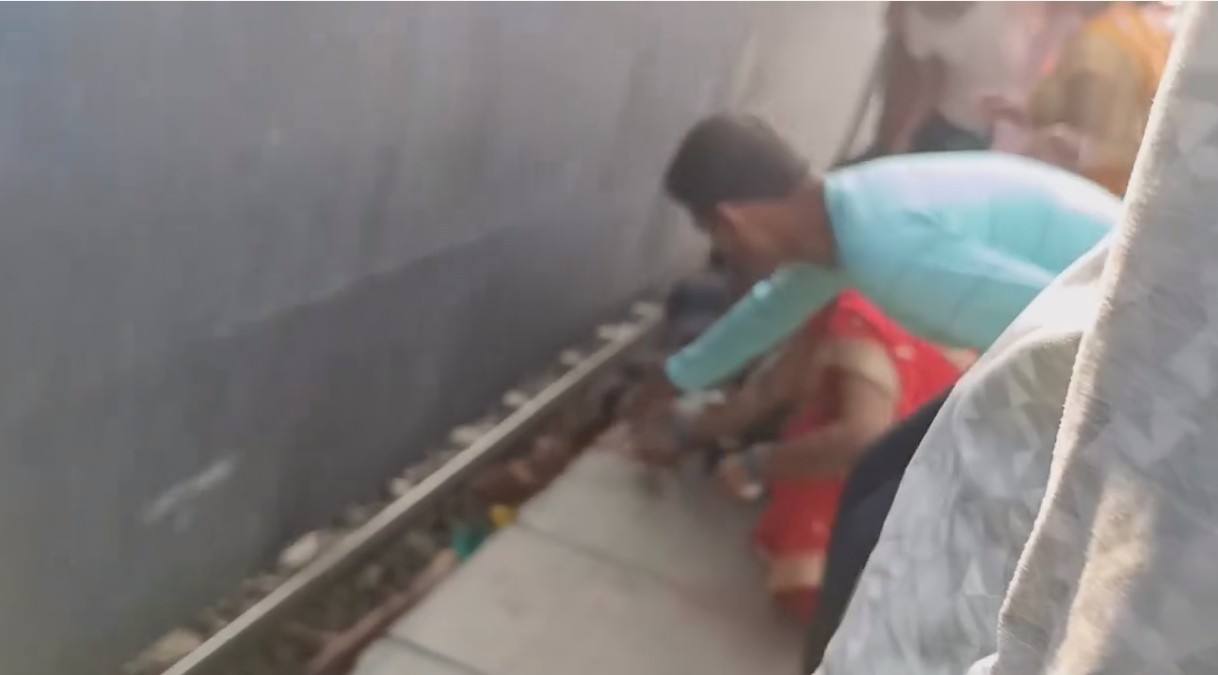 Family narrowly escapes after becoming trapped beneath a moving train while crossing railway tracks - India